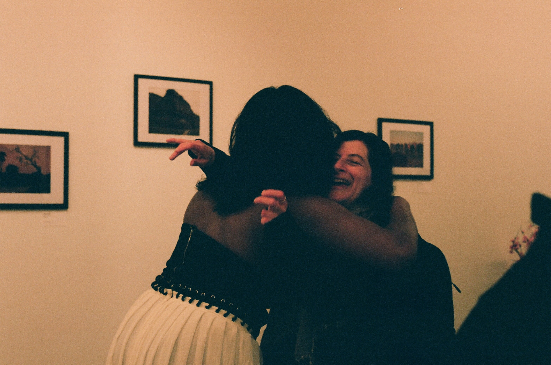 Two guests embracing and laughing at a gallery evening